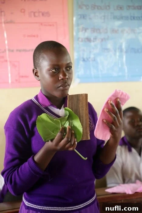 Uganda student holding leaves paper and cloth pad 