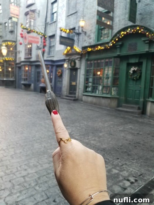 Hand wearing Harry Potter ring holding a wand in Diagon Alley 