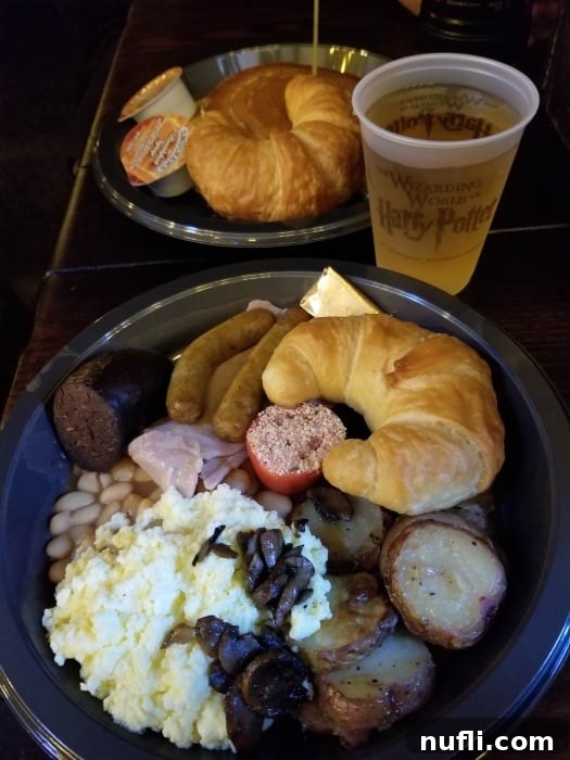 plate nwith bread, sausage, beans, and potatoes next to a Butter beer 