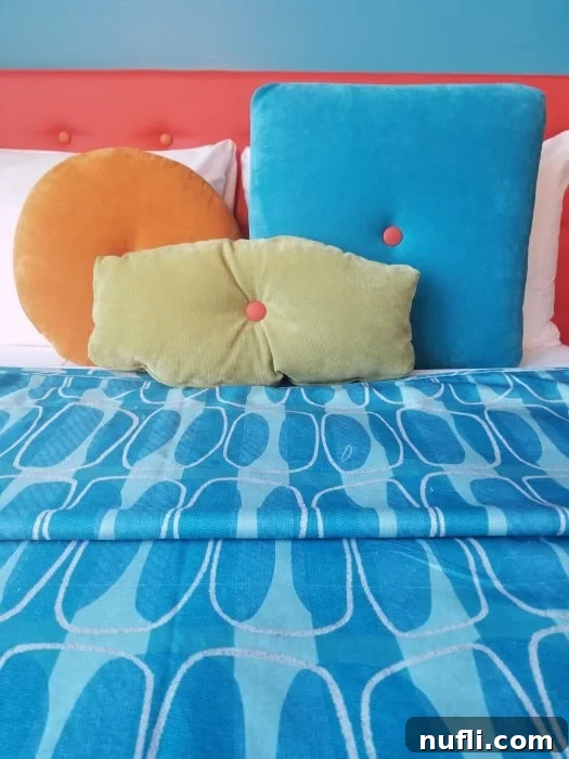 Close-up of a comfortable bed with a blue duvet and multicolored decorative pillows, embodying retro style
