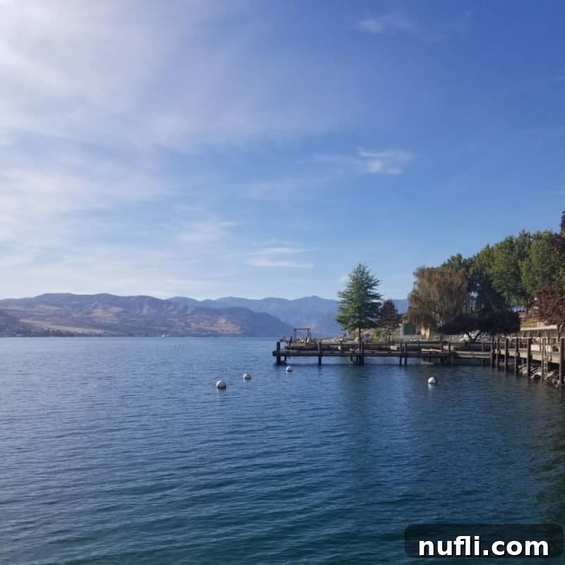 Scenic view looking down Lake Chelan with a dock on the side and majestic mountains in the background