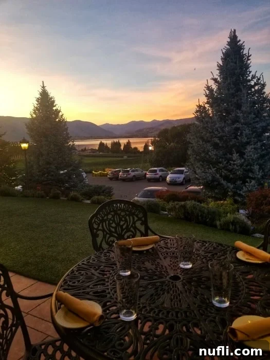 Breathtaking sunset over Lake Chelan from a dining table with chairs, settings, and a view of vineyards and rolling hills