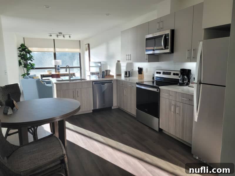 hotel room interior with full kitchen,, table, and views out to the water, 