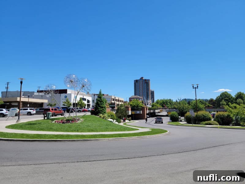 downtown area with dandelion metal scultpure, green grass, buildings, and bright blue sky