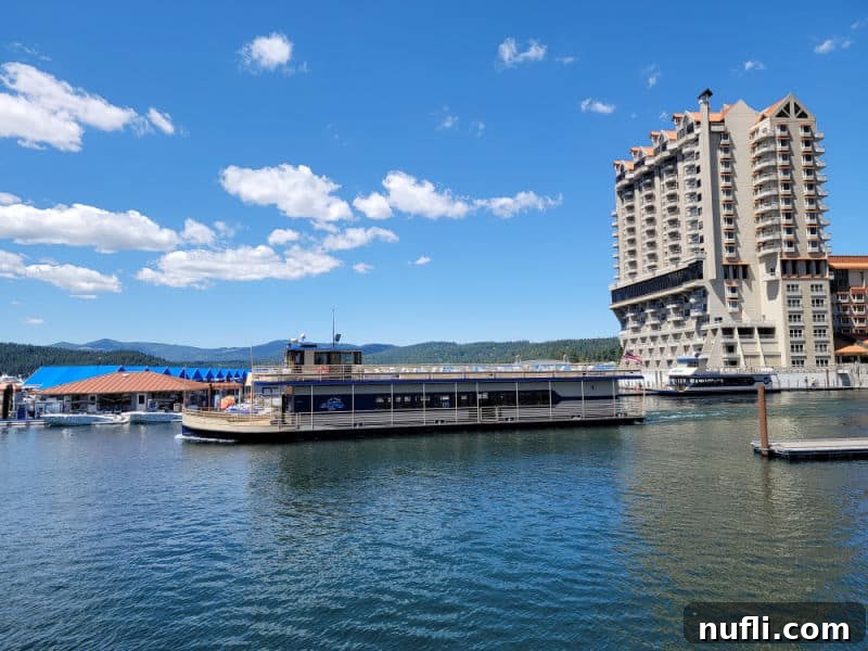 long boat on the lake CDA below the tall resort with a blue sky day and fluffy white clouds