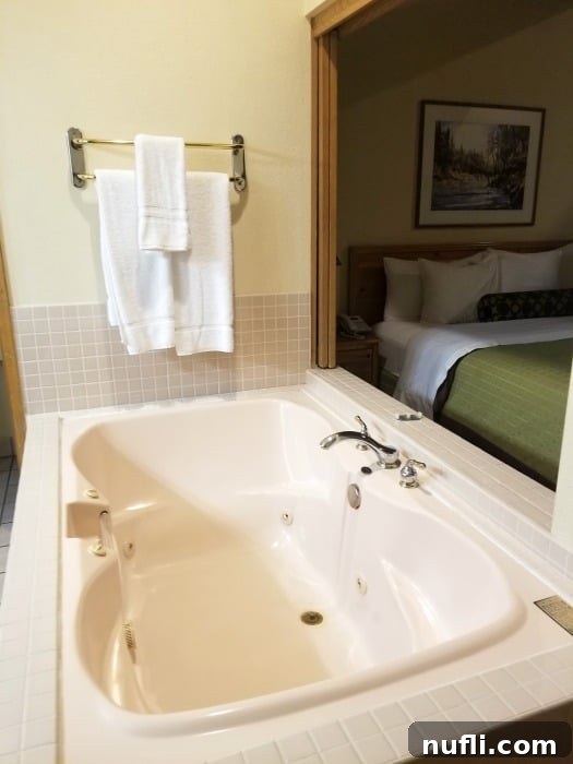 The Pines Resort - Bass Lake, California: A Video Tour 4 Large bathtub with a towel rack over it and a bed to the left in a resort suite