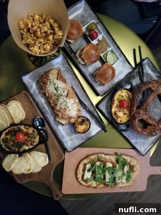 Table laden with appetizers including pretzels, popcorn, sliders, and small plates at Northern Quest's Taphouse