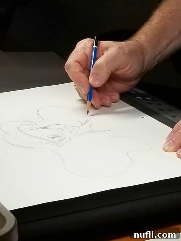Mark Henn expertly sketching Ariel, The Little Mermaid, on a white piece of paper