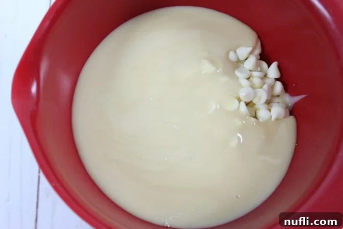 red bowl with sweetened condensed milk and white chocolate chips in it