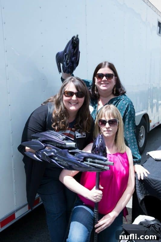 Tammilee and two women holding props from the Captain Marvel movie set, smiling brightly amidst the behind-the-scenes magic.