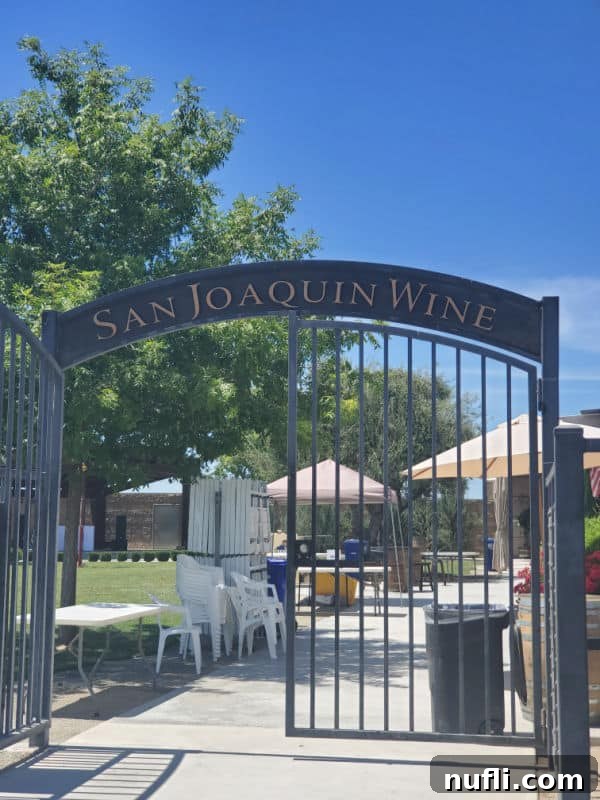 San Joaquin Wine's arched entrance, with umbrellas and chairs visible in the background, creating an inviting atmosphere.