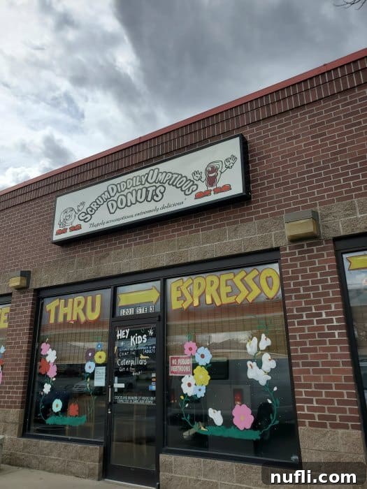 Scrumdiddilyumptious Donuts sign over glass windows with flowers painted on it