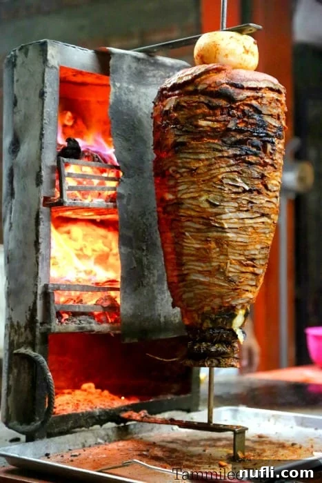 Ultimate Carne Asada Street Tacos 5 Marinated meat sizzling on a skewer in front of a fire, a common sight at street food stalls preparing tacos.