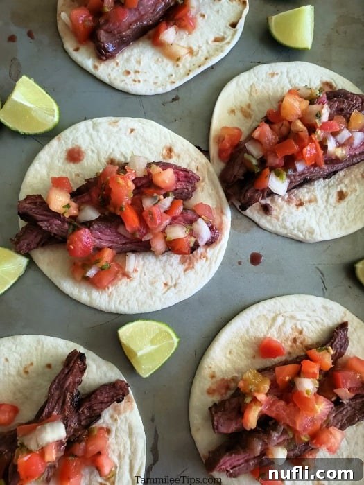 Ultimate Carne Asada Street Tacos 6 Carne Asada Street Tacos on a baking sheet with lime wedges, arranged beautifully and ready to be enjoyed.