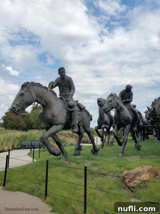 large sculpture of horse and riders on a grassy field