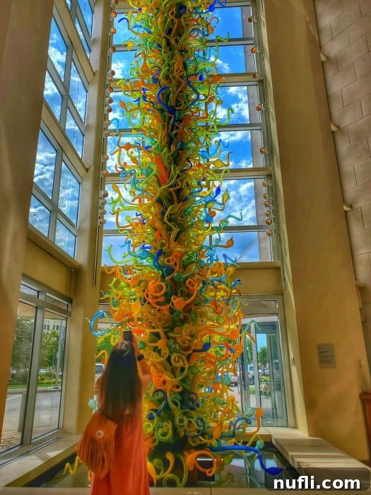 Amy taking a photo of the Chihuly glass sculpture with windows around it.