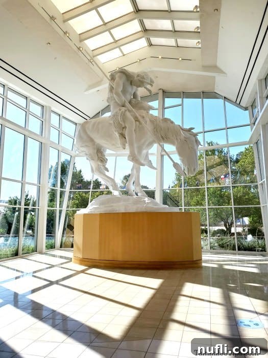 Large white native American and horse statue surrounded by windows.