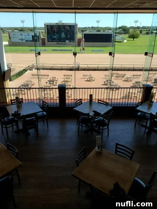 tables overlooking a dirt race track with large screens 