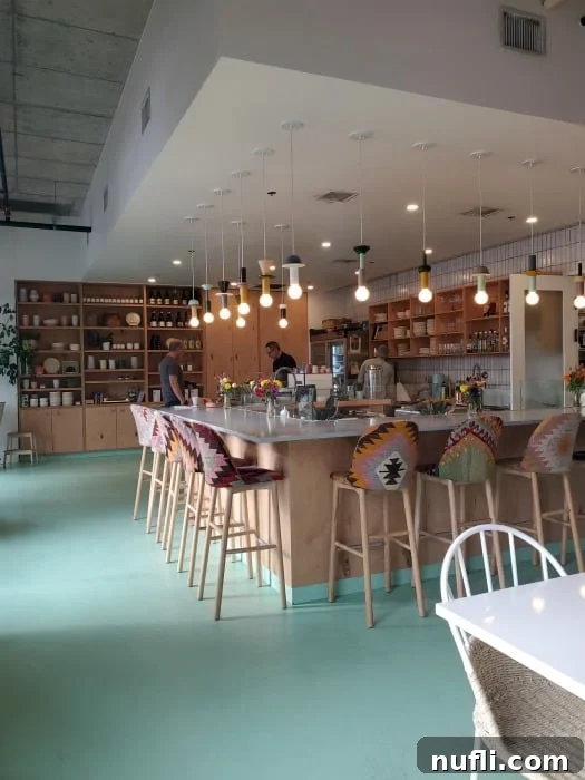 coffee shop with tall colorful stools, lights hanging from the ceiling, and shelves of dishware