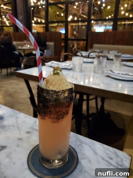 cocktail with a red and white striped straw on a white table in a restaurant 
