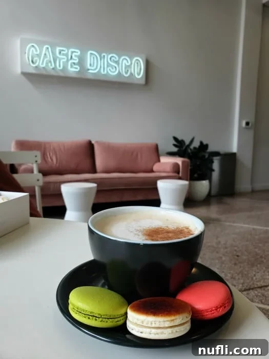 Cafe disco sign over a pink couch, chai and macaons on a black plate 