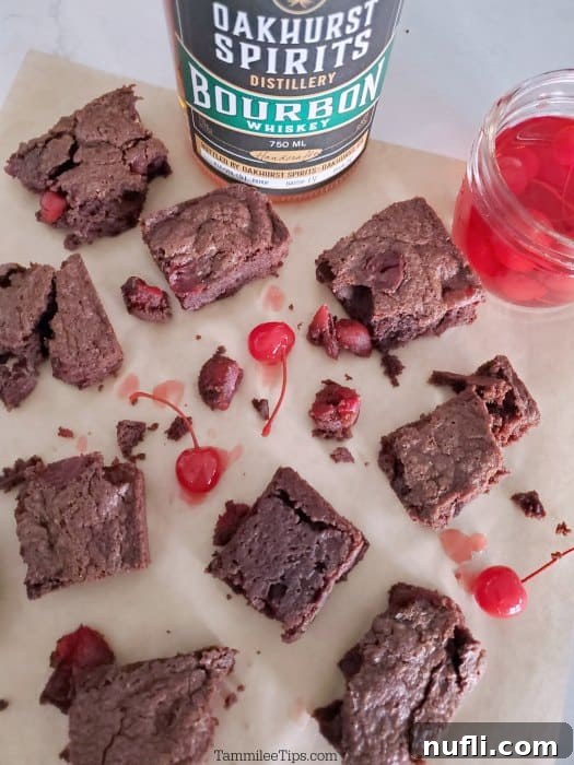 Fudgy Bourbon Cherry Brownies 3 Close-up of Bourbon Cherry Brownies on parchment paper next to a bottle of Oakhurst Spirits Bourbon, highlighting the rich color and texture.