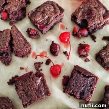 Fudgy Bourbon Cherry Brownies 5 Bourbon Cherry Brownies cut into perfect squares on parchment paper, adorned with glistening maraschino cherries.