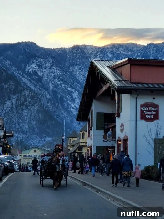 Snowy mountains in the background with a horse-drawn carriage coming down the main street of Leavenworth