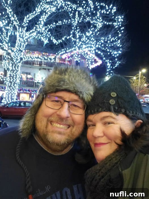 Tammilee and John standing with Christmas lights behind them in a tree in Leavenworth