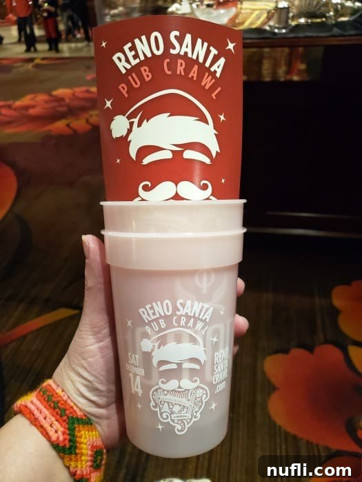 A hand proudly holding multiple Reno Santa Pub Crawl charity cups, showcasing the collectible items.