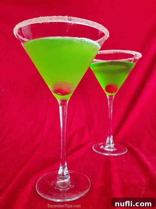 A vibrant green martini with a single maraschino cherry, set against a festive red background, capturing the holiday spirit.