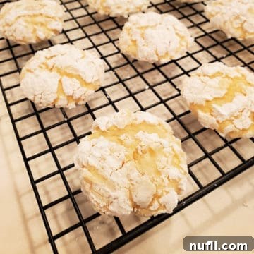 Lemon butter cookies cooling on a wire rack, freshly baked and dusted with powdered sugar.