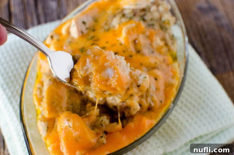 crockpot chicken and dressing in a glass bowl. Fork covered in food pulling up from the dish.