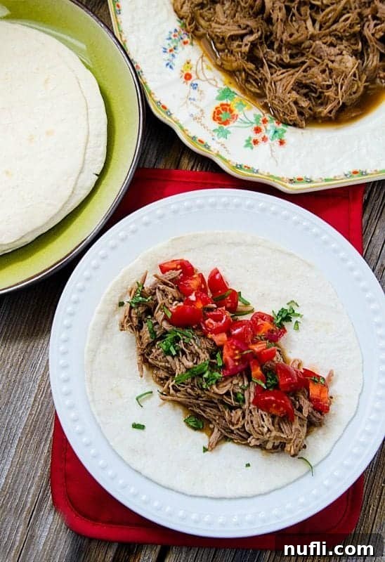 Serving of Mexican Pulled Pork alongside a plate with a finished taco, showcasing fresh toppings.