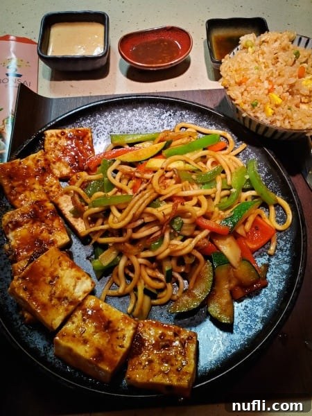 tofu, veggies, and noodles on a plate next to a bowl of rice