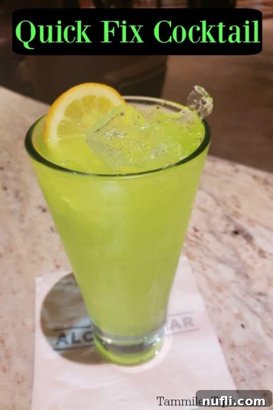 bright green cocktail in a tall glass with a white napkin