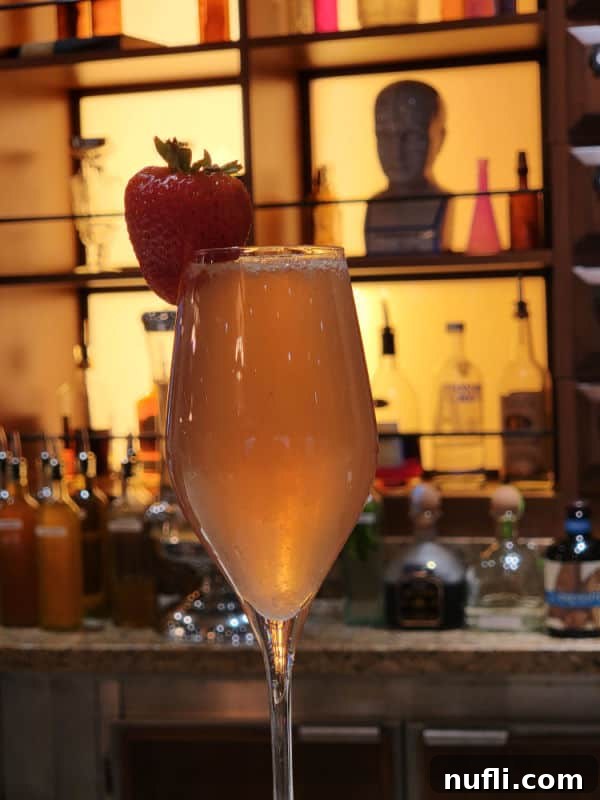 Carnival Alchemy Bar: The Signature French Kiss Cocktail 4 French Kiss Cocktail champagne flute with a strawberry garnish