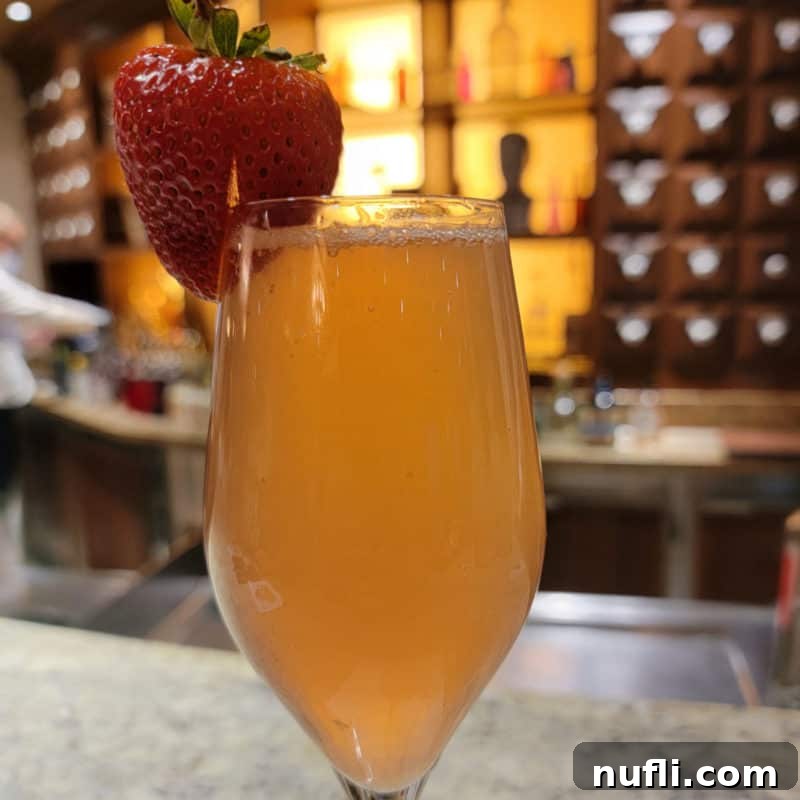 Carnival Alchemy Bar: The Signature French Kiss Cocktail 5 French Kiss Cocktail champagne flute with a strawberry garnish