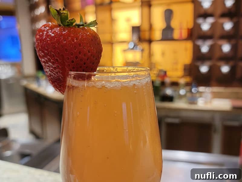 Carnival Alchemy Bar: The Signature French Kiss Cocktail 6 French Kiss Cocktail champagne flute with a strawberry garnish