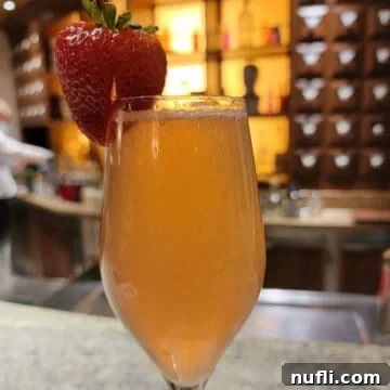 Carnival Alchemy Bar: The Signature French Kiss Cocktail 7 French Kiss cocktail in a champagne flute with a strawberry garnish