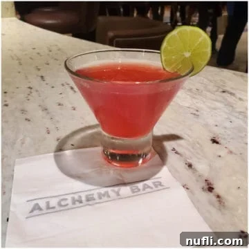 Alchemy Bar's Timeless Elixir Martini 4 Pink 40 is the new 20 Cocktail with a lime wheel on an Alchemy Bar napkin