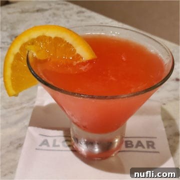 Martini Seduction Cocktail with an orange wheel in a stemless martini glass, vibrant and inviting.