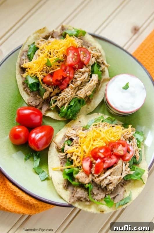 Easy Slow Cooker Mexican Chicken Tostadas 4 Crockpot chicken Tostada over a plate with tostadas piled with chicken, tomatoes and cheese.