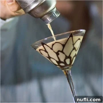 Decadent Tiramisu Martini 3 Tiramisu Martini pouring from a cocktail shaker into a martini glass with chocolate design.