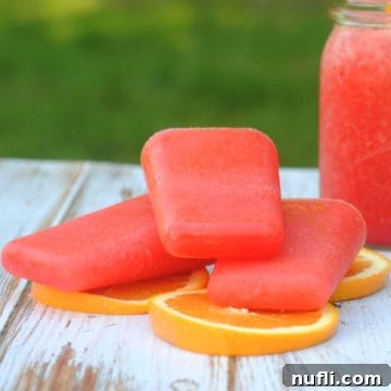 Hurricane Cocktail Ice Pops 3 Stacked Boozy Hurricane Popsicles on orange slices, positioned on a rustic picnic table, highlighting their refreshing appeal for outdoor summer enjoyment.