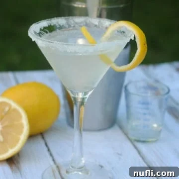 Lemon Drop Martini with sugared rim next to lemons and a cocktail shaker