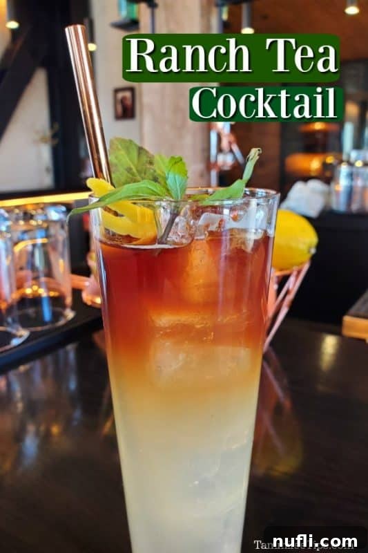 Signature Ranch Tea Cocktail 2 Ranch Tea cocktail in a tall glass with a metal straw sitting on a bar top, garnished with basil