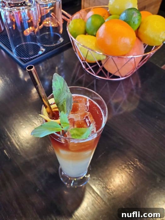 Ranch tea in a tall glass with a metal straw next to a bowl of lemons, limes, and oranges