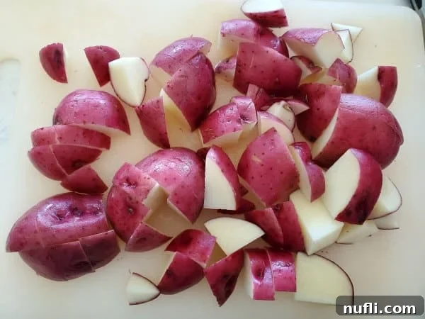 Red Breakfast Potatoes Recipe 3 Red potatoes expertly cut into bite-sized pieces on a wooden cutting board