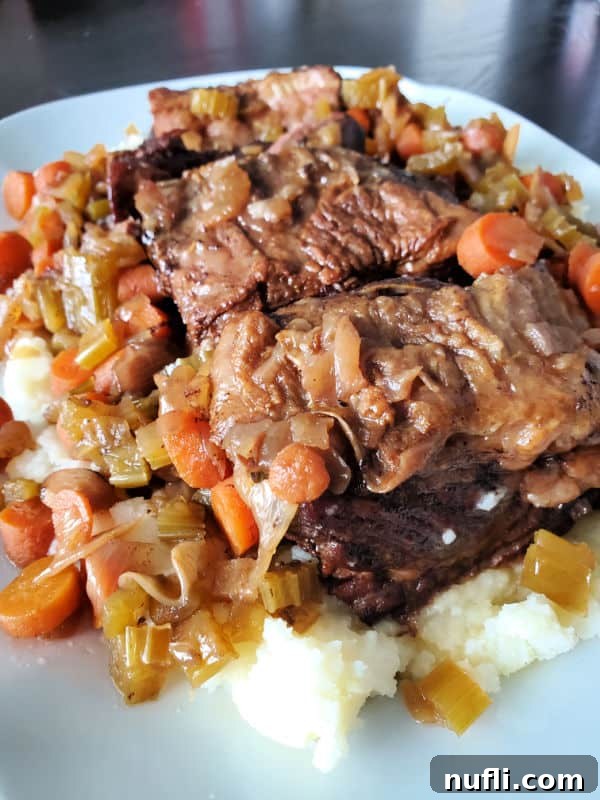Short ribs and vegetables on white rice on a white plate